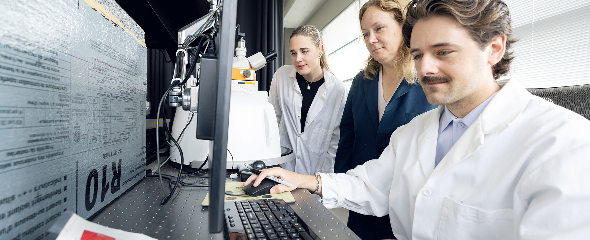 researchers in lab coats looking at a computer